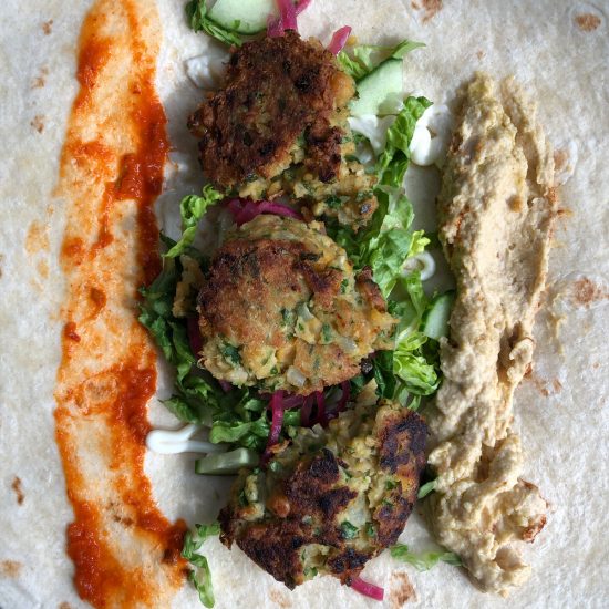 Falafel wrap with chili sauce, lettuce, cucumber, pickled onion, and hummus