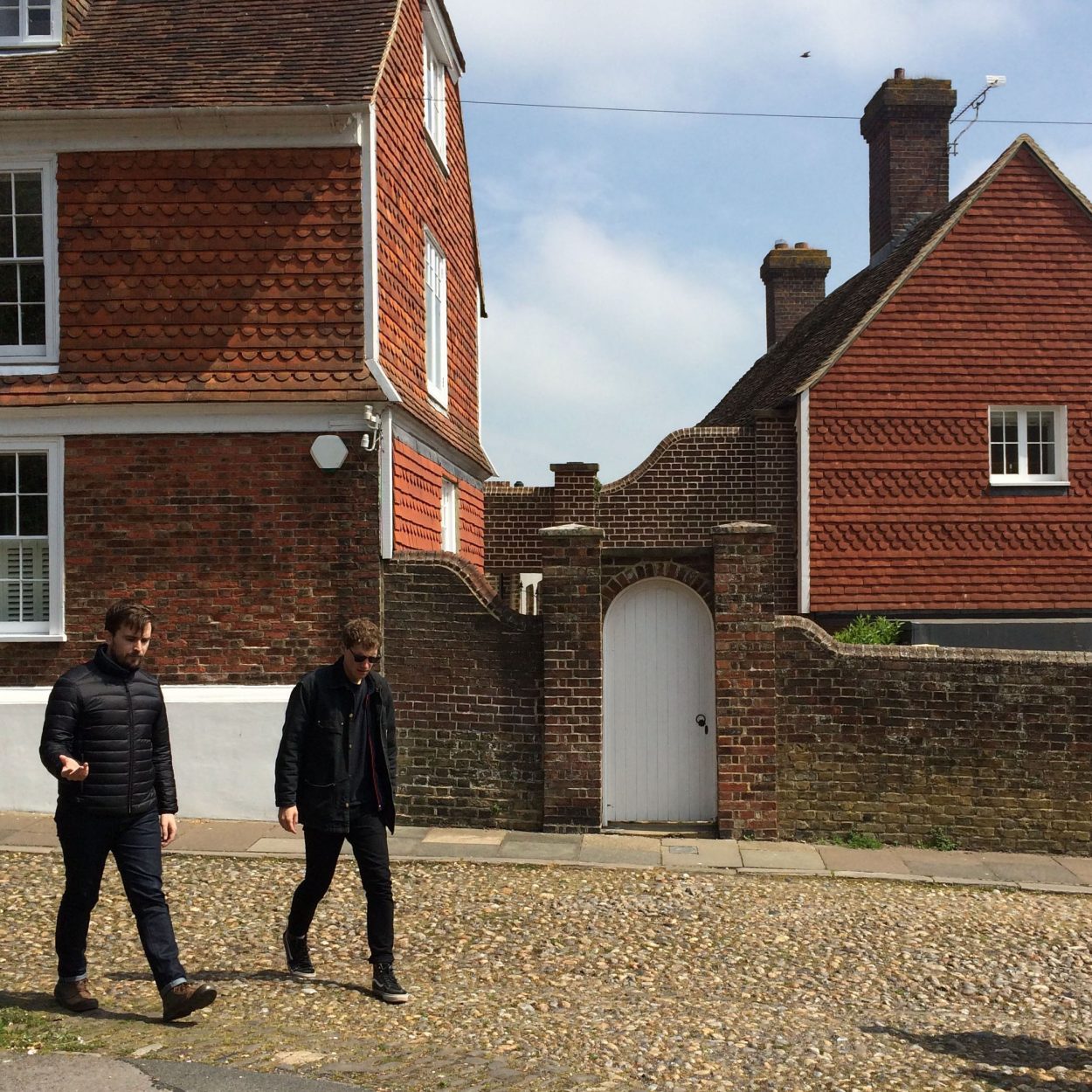 Two guys walking past brick houses in Rye
