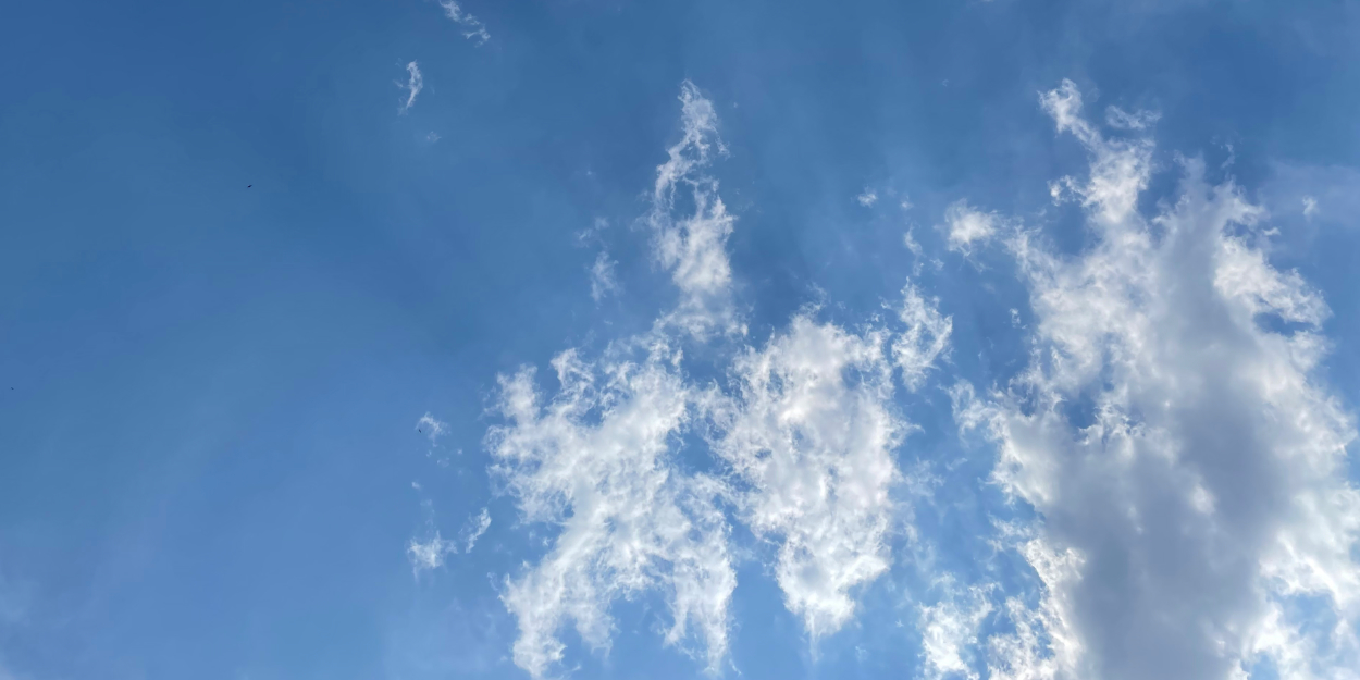 Clouds against a blue sky with sun rays coming through