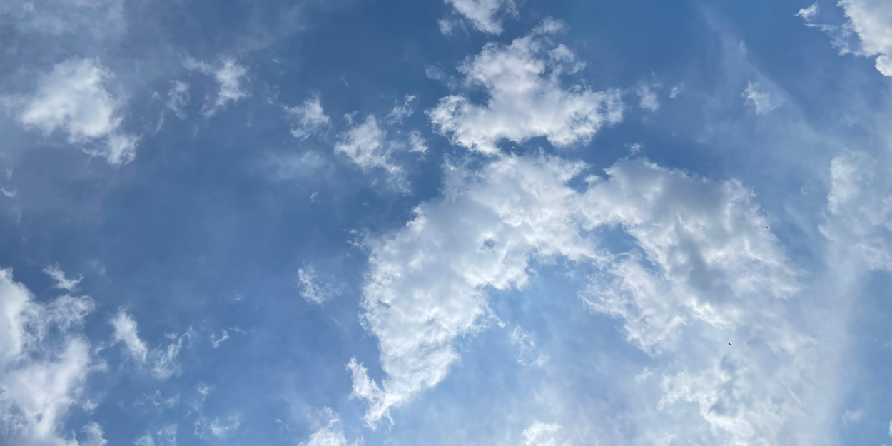 Clouds swirling in a blue sky with sun rays coming through